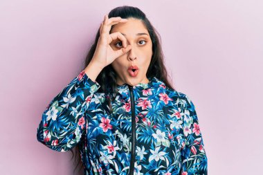 Güzel bir ortadoğulu kadın çiçek desenli bir ceket giyiyor. Şaşırmış bir yüz ve parmaklarından bakan bir gözle şaşırmış bir jest yapıyor. İnançsız ifade. 