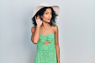 Yaz şapkası takan, ağzı kulaklarında gülümseyen genç Latin kız dedikoduları ve dedikoduları dinliyor. Sağırlık kavramı. 