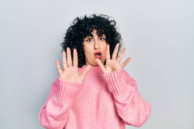 Orta Doğulu genç bir kadın gündelik giysiler giyip avuçlarını hareket ettiriyor. Korkmuş ve iğrenç bir ifadeyle reddediyor. Dur ve yasakla. 