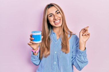 Kulak kiri çıkartan güzel İspanyol kadın gülümsüyor mutlu bir şekilde elini ve parmağını yana doğru gösteriyor. 