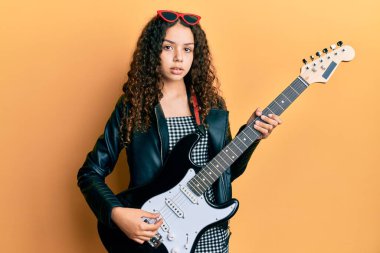 Elektro gitar çalan genç İspanyol kız yüzünde ciddi bir ifadeyle rahatladı. Basit ve doğal bir şekilde kameraya bakıyorsun.. 