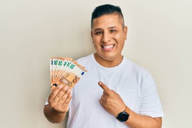 Elinde 50 avroluk banknotlar tutan genç Latin adam gülümsüyor. 