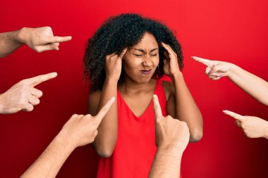 Afro saçlı güzel bir Afro-Amerikalı kadın etrafta parmaklarıyla kendini işaret ediyor. Başı ağrıyor çünkü stres altında. migren ağrısı. 