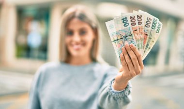 Genç sarışın kız gülümsüyor. Elinde Çech Koruna banknotları var..