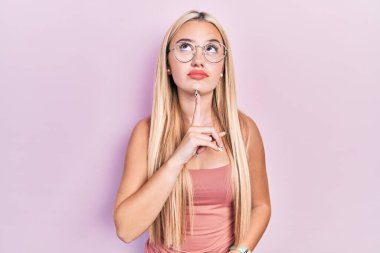 Gündelik kıyafetler giyen genç sarışın kız şüphe üzerine yoğunlaşmıştı. Parmakları çenesinde ve yukarı bakıyordu. 