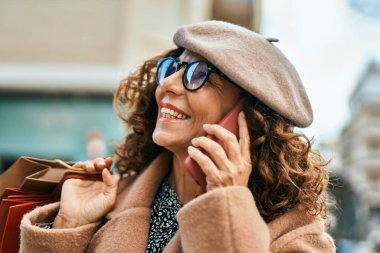 Şehirdeki akıllı telefondan konuşan orta yaşlı İspanyol kadın..