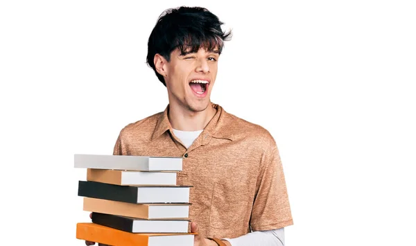 Joven Hipster Guapo Sosteniendo Montón Libros Guiñando Ojo Mirando Cámara — Foto de Stock