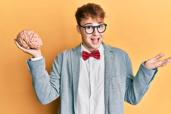 Joven Hombre Caucásico Con Gafas Sosteniendo Cerebro Celebrando Logro Con —  Fotos de Stock