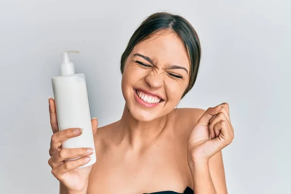 Jovem Morena Segurando Creme Facial Hidratante Cosmético Gritando Orgulhoso Celebrando — Fotografia de Stock