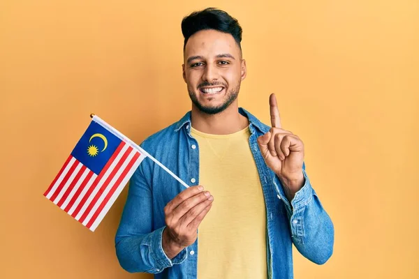 Young Arab Man Holding Malaysia Flag Smiling Idea Question Pointing — Stock Photo, Image