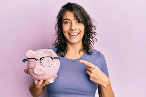 Joven Mujer Hispana Sosteniendo Alcancía Con Gafas Sonriendo Feliz Señalando —  Fotos de Stock