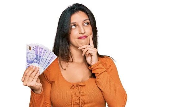 Beautiful Hispanic Woman Holding Swedish Krona Banknotes Serious Face Thinking — Stock Photo, Image