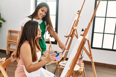 Öğrenci ve öğretmen resim yaparken gülümsüyor..