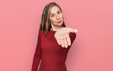 Gündelik kıyafetler giyen, neşeli gülümseyen, yardım eli uzatan ve kabullenen genç sarışın kadın.. 