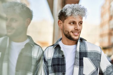 Genç İspanyol adam gülümseyerek şehirde mutlu mesut dikiliyor..