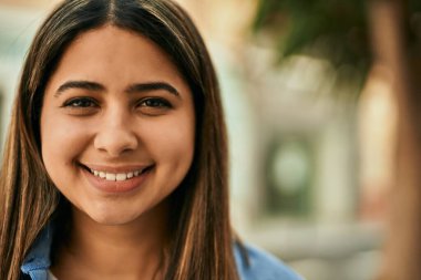 Genç Latin kız gülümseyerek şehirde mutlu mesut dikiliyor..