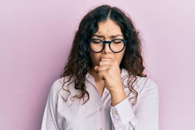 Kıvırcık saçlı, günlük kıyafetler giyen ve gözlük takan genç esmer kadın kendini iyi hissetmiyor ve soğuk algınlığı veya bronşitin belirtisi olarak öksürüyor. sağlık hizmeti kavramı. 