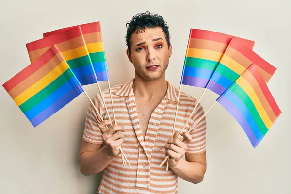 Hombre Guapo Usando Maquillaje Sosteniendo Banderas Arco Iris Lgbtq Escéptico —  Fotos de Stock