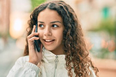 Güzel İspanyol kız gülümsüyor. Şehirdeki akıllı telefondan konuşuyor..