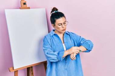 Genç İspanyol kadın boyacı sehpasında durup kol saati saatini kontrol ediyor, rahat ve kendinden emin. 