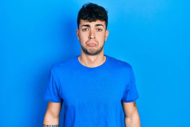 Günlük mavi tişört giyen genç İspanyol bunalımlı ve üzüntülü, sinirli ve korkmuş bir şekilde ağlıyor. hüzünlü ifade. 