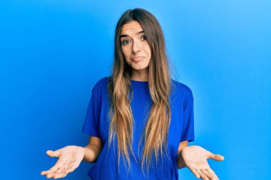 Gündelik kıyafetler giyen, elleri ve kolları havada, kafası karışmış genç İspanyol kadın. şüphe kavramı. 