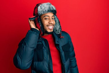 Sakallı, kışlık şapkalı ve paltolu genç Afro-Amerikan bir adam kulağından girip kulağına gelen dedikoduları ya da dedikoduları dinliyor. Sağırlık kavramı. 