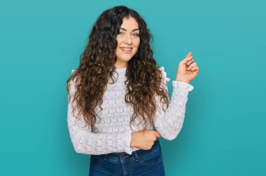 Gündelik kıyafetler giyen genç İspanyol kız gülümseyerek mutlu bir şekilde elini ve parmağını kenarda gezdiriyor. 