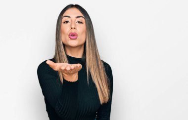 Gündelik giysiler giymiş genç İspanyol bir kadın kameraya bakıp havada bir öpücük savuruyor ve sevimli ve seksi oluyor. aşk ifadesi. 