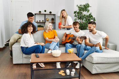 Partide gülümseyen ve evde klasik gitar çalan bir grup genç arkadaş..