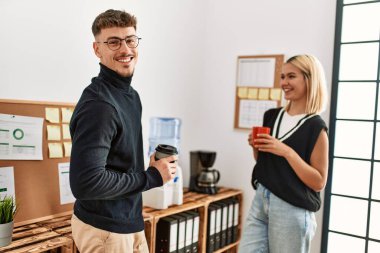 İki iş adamı gülümsüyor, ofiste kahve içiyorlar..