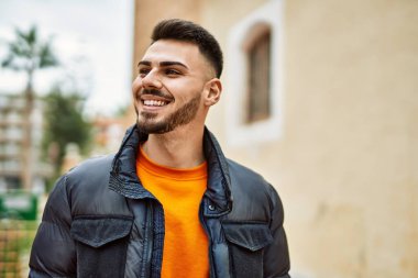 Yakışıklı, sakallı, neşeli ve kendine güvenen, kışlık palto giyen bir İspanyol.