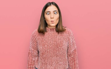 Gündelik kıyafetler giyen, dudaklarıyla balık suratı yapan, çılgın ve komik bir jest yapan genç ve güzel bir kadın. Komik ifade. 