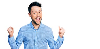 Sıradan iş gömleği giyen İspanyol bir adam kollarını kaldırıp gözleri açık bir şekilde başarıyı kutluyor ve şaşırıyor. Kazanan konsept. 