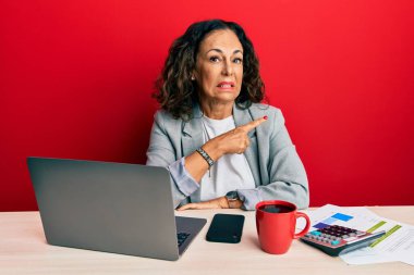 Ofiste çalışan orta yaşlı güzel bir kadın bir fincan kahve içiyor. Endişeli ve endişeli bir ifade takınıyor. 