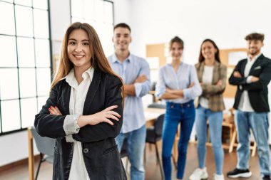 Genç iş adamlarından oluşan bir grup mutlu bir şekilde ayakta durup ofiste el kol hareketleriyle gülüyor..