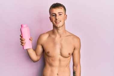 Genç beyaz adam elinde şampuan şişesi tutuyordu. Olumlu ve mutlu görünüyordu. Kendine güvenen bir gülümsemeyle dişlerini gösteriyordu. 