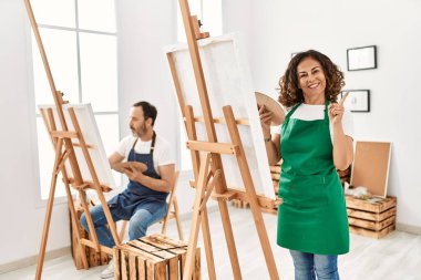 İspanyol orta yaşlı kadın ve sanat stüdyosunda olgun bir adam gülümsüyor. 