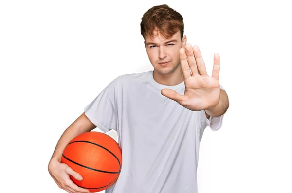 年轻的高加索人张开手拿着篮球 做停止手势 表情严肃而自信 防守姿势端庄 — 图库照片
