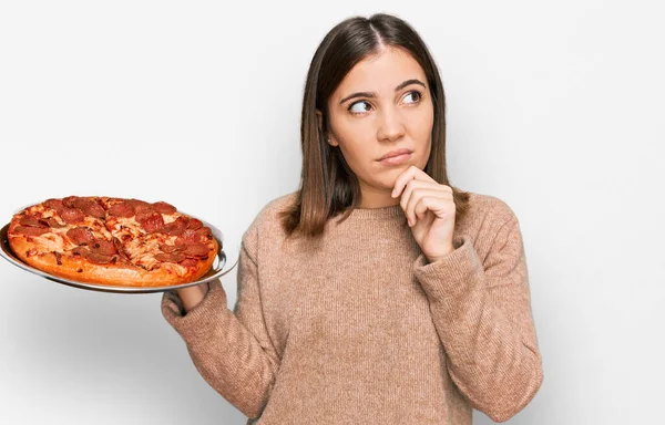 Jovem Mulher Bonita Segurando Pizza Italiana Rosto Sério Pensando Questão — Fotografia de Stock