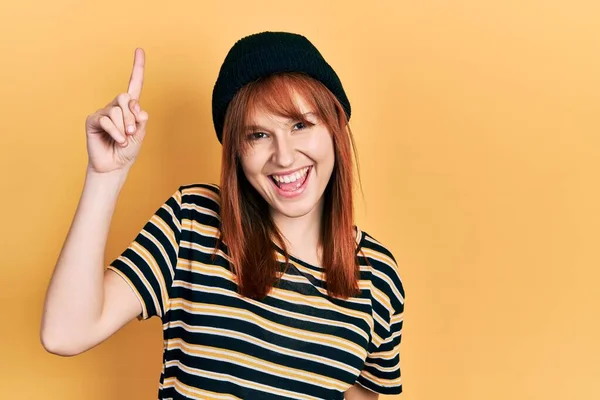 Rödhårig Ung Kvinna Med Ullmössa Pekande Finger Upp Med Lyckad — Stockfoto