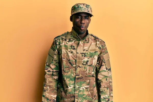 軍隊の制服を着た若いアフリカ系アメリカ人は 狂気とコミカルなジェスチャーで魚の顔を作ります 面白い表現 — ストック写真