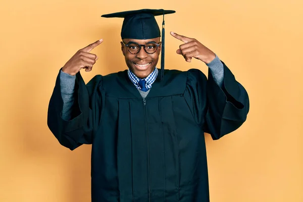 Jovem Afro Americano Vestindo Boné Formatura Roupão Cerimônia Sorrindo Apontando — Fotografia de Stock