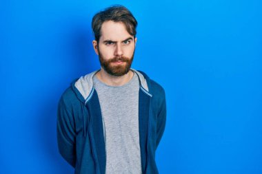 Sakallı, sıradan bir kazak giyen, kuşkucu ve gergin, sorun yüzünden suratını asan beyaz bir adam. negatif kişi. 