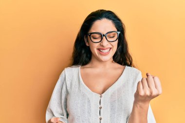 Güzel ortadoğulu kadın gündelik giysiler ve gözlük takarak başarıyı kolları havada ve gözleri kapalı kutluyor. 