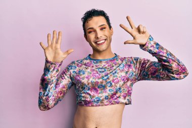 Makyaj giysileri giymiş yakışıklı bir adam 8 numarayı gösterip işaret ederken kendinden emin ve mutlu bir şekilde gülümsüyor.. 