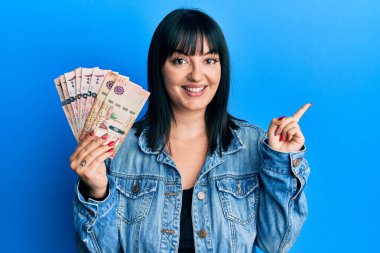 Suudi Arabistan 'ın riyal banknotlarını tutan genç İspanyol kadın gülümsüyor. 