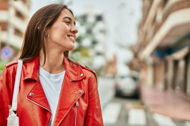 Genç İspanyol kadın gülümseyerek şehirde mutlu mesut dikiliyor..