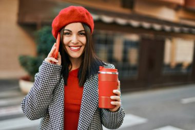 Genç İspanyol kadın akıllı telefondan konuşuyor ve şehirde kahve içiyor..