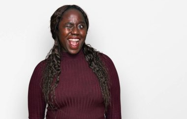 Sıradan bir kazak giyen genç Afrikalı kadın kameraya seksi bir ifadeyle bakıyor, neşeli ve mutlu bir yüzle.. 